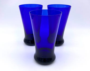 Può includere: Tre bicchieri in vetro blu cobalto con bordo svasato e base arrotondata.