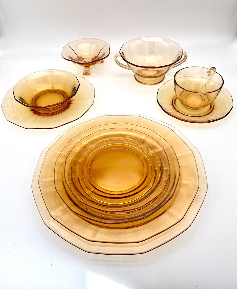 Puede incluir: Conjunto de platos de vidrio &aacute;mbar, que incluye un taz&oacute;n peque&ntilde;o con pedestal, un taz&oacute;n m&aacute;s grande con dos asas, un platillo, una taza de t&eacute; y un juego de tres platos anidados.