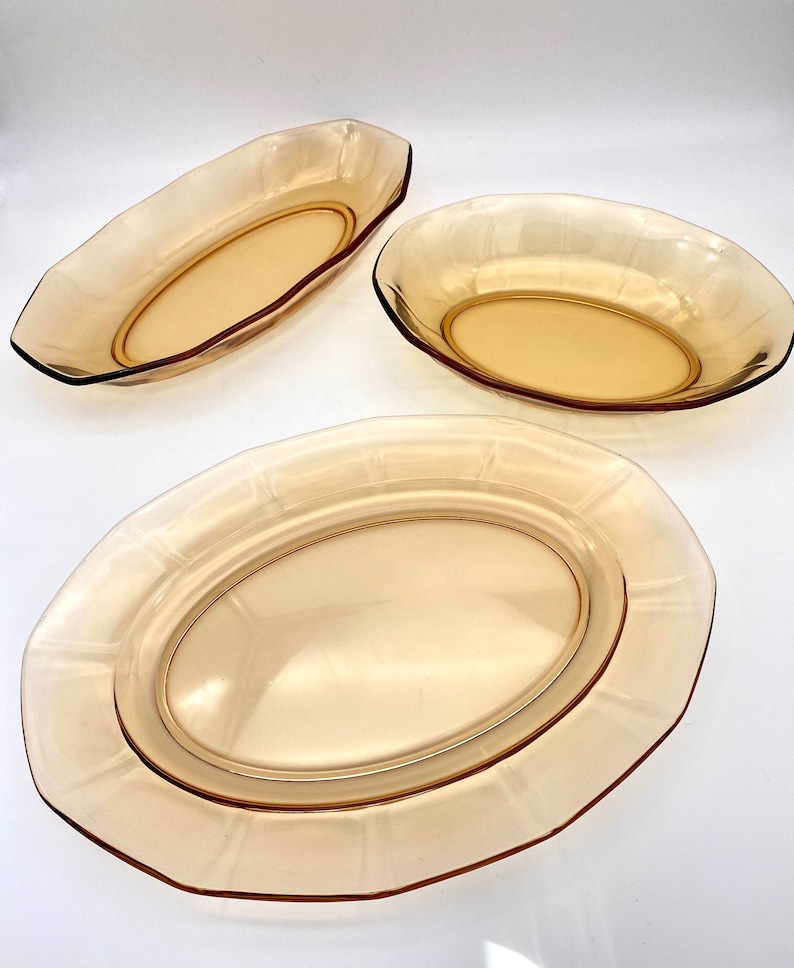 Puede incluir: Juego de tres platos ovalados para servir de vidrio &aacute;mbar. Los platos tienen un borde elevado y una superficie lisa ligeramente texturizada.