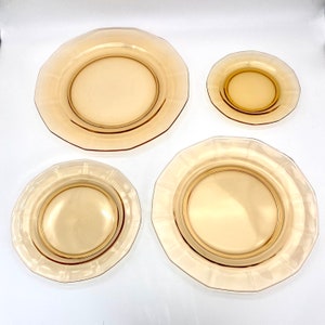 Puede incluir: Juego de cuatro platos de vidrio &aacute;mbar con bordes festoneados. Los platos son de diferentes tama&ntilde;os, siendo el plato m&aacute;s grande el m&aacute;s prominente.