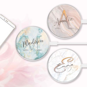 May include: Three personalized wireless phone chargers with marble-like designs. One charger has a teal and gold pattern with the name "Madison". Another has a beige and pink pattern with the name "Amelia". The third has a white and gray pattern with the name "Emma".