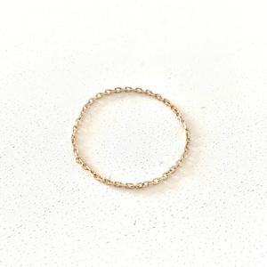 May include: A delicate gold chain ring. The ring is made of a thin chain that is linked together to form a circle.