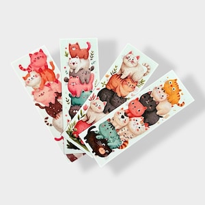 May include: Four rectangular bookmarks featuring stacks of cartoon cats in various colors. Each bookmark has a different arrangement of cats, with some decorated with floral accents. The cats have smiling faces and are in shades of pink, orange, black, and white.