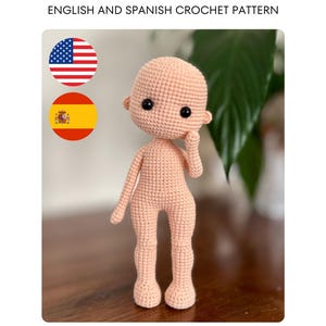 Peut inclure: Une poupée crochetée de couleur pêche clair, avec des yeux noirs et de petites oreilles. La poupée a une forme de corps simple et arrondie avec des bras et des jambes. L'image comprend le texte "ENGLISH AND SPANISH CROCHET PATTERN" et les drapeaux des États-Unis et de l'Espagne.