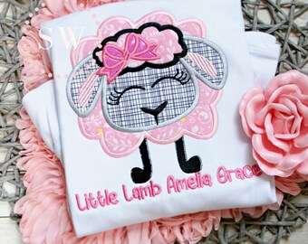 May include: White onesie with a pink and gray embroidered lamb with a pink bow. The onesie has the text "Little Lamb Amelia Grace" embroidered on the bottom.