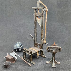 Puede incluir: Guillotina de madera en miniatura con una cuchilla afilada, un hacha pequeña, un dado y un cepo de madera. La guillotina tiene un sistema de cuerda y polea. Los artículos están pintados en tonos marrones y grises.