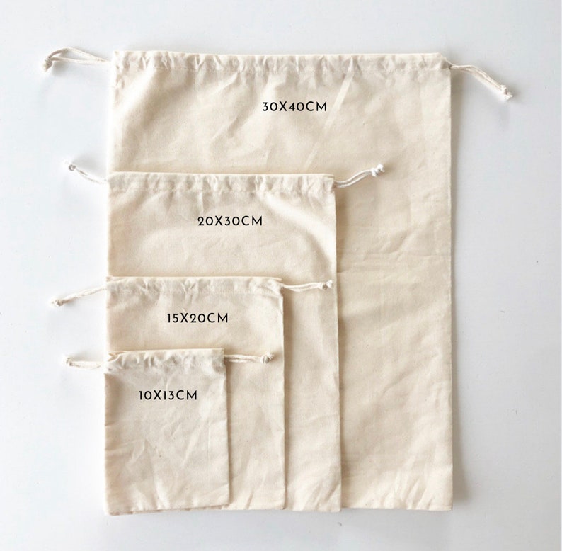 May include: Four off-white drawstring bags made of fabric, arranged by size from smallest to largest. The bags are labeled with the dimensions 10x13cm, 15x20cm, 20x30cm, and 30x40cm. Each bag features a simple pull-string closure at the top opening.