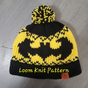 May include: Black and yellow knit hat with a pom pom on top. The hat features a Batman logo. The hat has a tag that says "Loom Knit Pattern" and "Hand Made".