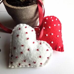 May include: Two felt heart ornaments with red and white polka dots. The hearts are attached to a red ribbon.