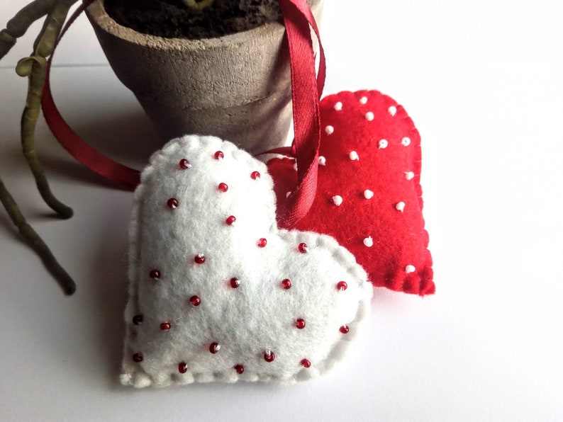 May include: Two felt heart ornaments with red and white polka dots. The hearts are attached to a red ribbon.
