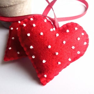 May include: Two red felt hearts with white polka dots, sewn together with a red ribbon.