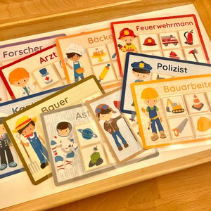 Puede incluir: Un conjunto de nueve tarjetas coloridas con ilustraciones de diferentes profesiones. Cada tarjeta tiene un t&iacute;tulo en alem&aacute;n, como "Forscher" (investigador), "Arzt" (m&eacute;dico) y "B&auml;cker" (panadero). Las tarjetas est&aacute;n dise&ntilde;adas para que los ni&ntilde;os aprendan sobre diferentes trabajos.