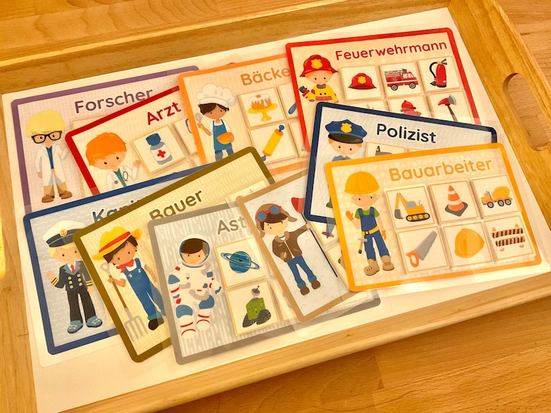 Puede incluir: Un conjunto de nueve tarjetas coloridas con ilustraciones de diferentes profesiones. Cada tarjeta tiene un t&iacute;tulo en alem&aacute;n, como "Forscher" (investigador), "Arzt" (m&eacute;dico) y "B&auml;cker" (panadero). Las tarjetas est&aacute;n dise&ntilde;adas para que los ni&ntilde;os aprendan sobre diferentes trabajos.