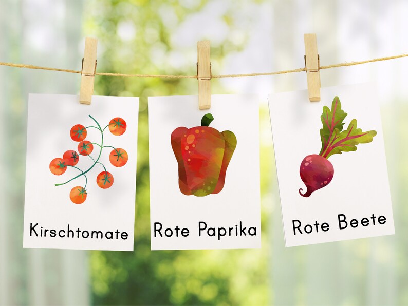 May include: Three watercolor illustrations of vegetables hanging on a clothesline. The first illustration is of cherry tomatoes on a vine. The second illustration is of a red bell pepper. The third illustration is of a red beet. The text below each illustration reads "Kirschtomaten", "Rote Paprika", and "Rote Beete".
