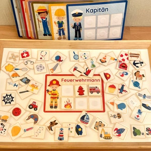 Puede incluir: Una bandeja de madera con una superficie blanca que contiene una variedad de tarjetas ilustradas de colores. Las tarjetas muestran im&aacute;genes de diferentes profesiones, incluyendo un bombero, un capit&aacute;n y un polic&iacute;a. Las tarjetas est&aacute;n dispuestas en un patr&oacute;n de cuadr&iacute;cula en la bandeja. La bandeja est&aacute; hecha de madera y tiene un acabado marr&oacute;n claro.