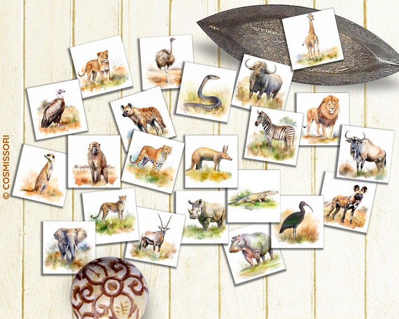 May include: A collection of square watercolor illustrations of African animals, including lions, giraffes, zebras, and elephants. The artwork is arranged on a light wooden surface, with a decorative metal leaf-shaped dish.