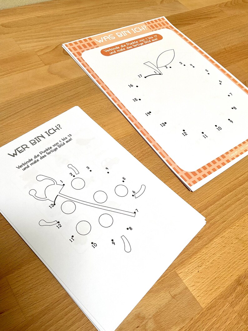 May include: Two black and white connect-the-dots activity sheets. One sheet features a ladybug and the other sheet features an apple. The sheets have the instructions "Wer bin ich?" and "Was bin ich?" printed on them.