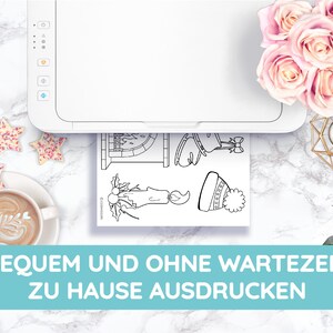 May include: A white printer printing black and white line art of Christmas-themed illustrations. The image includes a cup of coffee, star-shaped cookies, and pink roses. The text at the bottom reads, "BEQUEM UND OHNE WARTEZEIT ZU HAUSE AUSDRUCKEN."