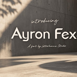 Puede incluir: Una pantalla gráfica digital que presenta el texto introducing Ayron Fexa A font by Letterhanna Studio en una tipografía blanca sin remates. El texto se coloca contra una pared de hormigón con una gran estructura de hormigón curva a la derecha.