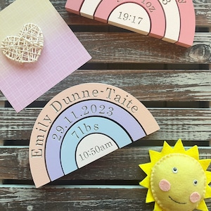 Könnte beinhalten: Zwei regenbogenfarbene Holzbögen mit gravierten Details. Der obere Bogen ist rosa und weiß und trägt die Aufschrift "Harper Murphy 30.11.2023 9lbs 1oz 19:17". Der untere Bogen ist pfirsichfarben, lila und blau und trägt die Aufschrift "Emily Dunne-Taite 29.11.2023 7lbs 10:50am".