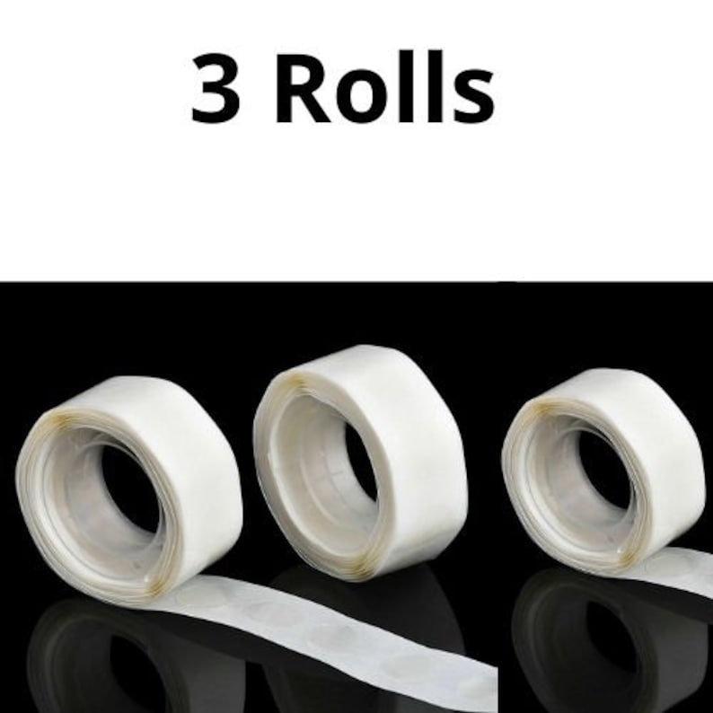 May include: Three rolls of clear double-sided adhesive tape. Each roll is about 1.5 inches wide and has a white core. The tape is designed for hanging lightweight items.