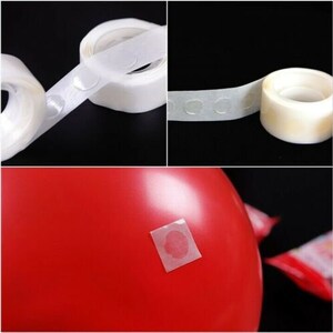 May include: A roll of clear adhesive dots for attaching balloons to a surface. The dots are on a white tape roll. A red balloon is shown with a dot attached to it.