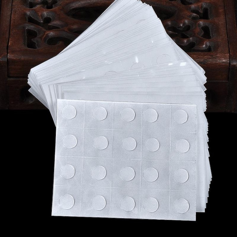May include: A sheet of white adhesive dots, arranged in a grid pattern. The dots are designed for crafts, scrapbooking, and other DIY projects.