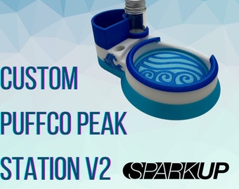 May include: Custom Puffco Peak Station V2 with a blue and white wave design. The station has a small container for concentrates and a larger container for tools.