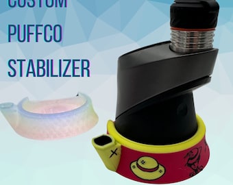 May include: Custom Puffco Stabilizer with a pink, yellow, and black design. The stabilizer is made of silicone and has a small spout on the side. The text "SPARKUP" is printed in black on a white background below the stabilizer.
