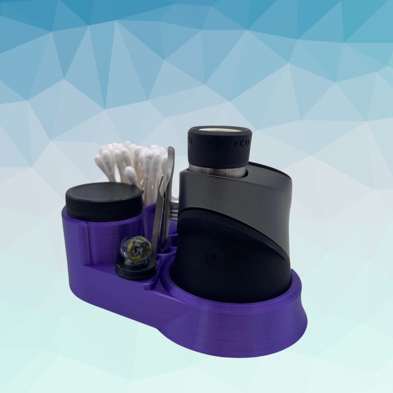 K&ouml;nnte beinhalten: Lilafarbener 3D-gedruckter Organizer mit einem schwarzen und silbernen Vaporizer, einem kleinen Glas, Wattest&auml;bchen und einem Werkzeug. Der Organizer hat eine strukturierte Oberfl&auml;che.