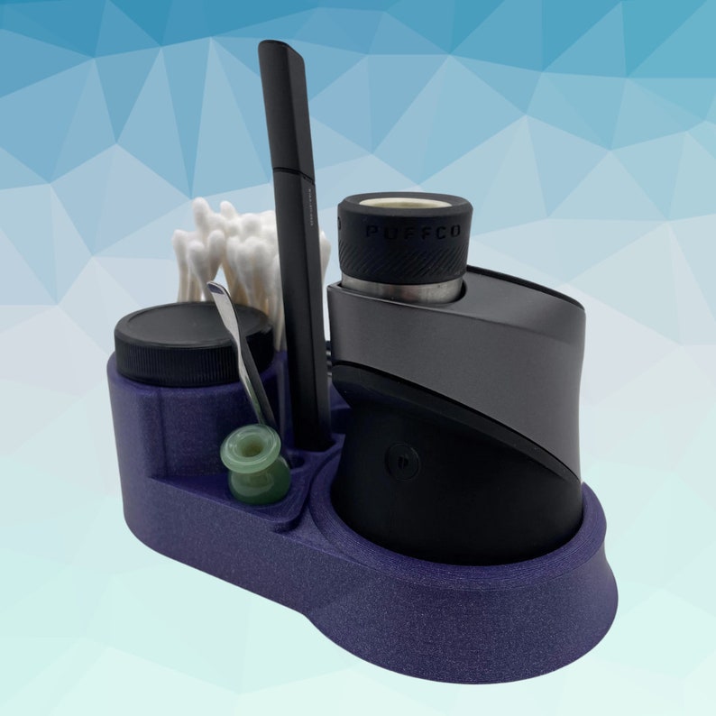 K&ouml;nnte beinhalten: Ein lila Organizer mit F&auml;chern f&uuml;r einen Vape-Stift, ein kleines Glas, ein Werkzeug und Wattest&auml;bchen. Der Vape-Stift ist schwarz und hat eine silberne Basis mit dem Wort "PUFFCO" darauf.