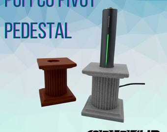 May include: A gray and brown pedestal stand for a Puffco Pivot vaporizer. The stand has a cylindrical base with a fluted design. The stand is made of a textured material and has a black cord attached to it.