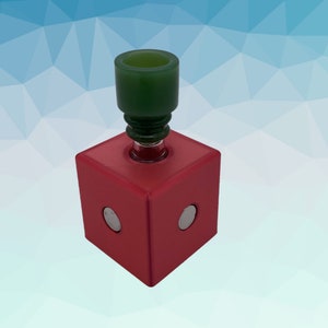 Puede incluir: Un cubo rojo con dos c&iacute;rculos plateados en la parte delantera. Un cuenco de vidrio verde se asienta en la parte superior del cubo.