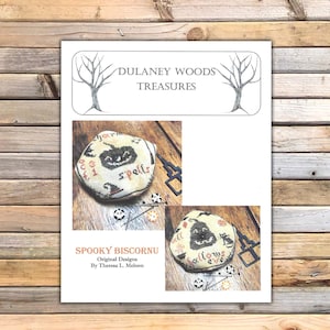 Puede incluir: Un patrón de punto de cruz para un biscornu espeluznante con una calabaza con una cara de jack-o'-lantern y el texto "spells" y "hallowe'en". El patrón es de Theresa L. Meloon y forma parte de la colección Dulaney Woods Treasures.