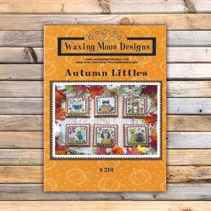 Peut inclure: Un livret de modèles de point de croix intitulé Autumn Littles par Waxing Moon Designs, numéro 213. La couverture orange présente un motif de citrouilles répétitif et une image centrale de six petits motifs carrés d'animaux des bois.
