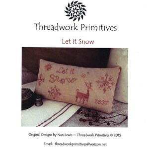 Puede incluir: Un cojín rectangular de tela beige con bordado de punto de cruz en hilo rojo. El diseño incluye el texto "Let it Snow", un reno, varios patrones de copos de nieve y el año "1837". El logotipo "Threadwork Primitives" está arriba.
