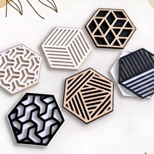 May include: Seven hexagonal coasters with diverse geometric patterns. The coasters are in natural wood, black, and white. Designs include linear patterns, geometric shapes, and openwork details. Suitable for home decor, these coasters measure approximately 10 cm across.