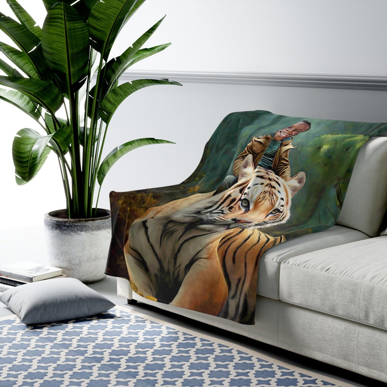 May include: A soft, plush throw blanket featuring a colourful illustration of a tiger and a person riding on its back. The background is a green jungle scene.