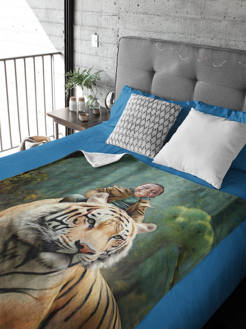 May include: A blue fleece blanket featuring a printed image of a tiger with a person riding on its back. The image is set against a green and blue background.