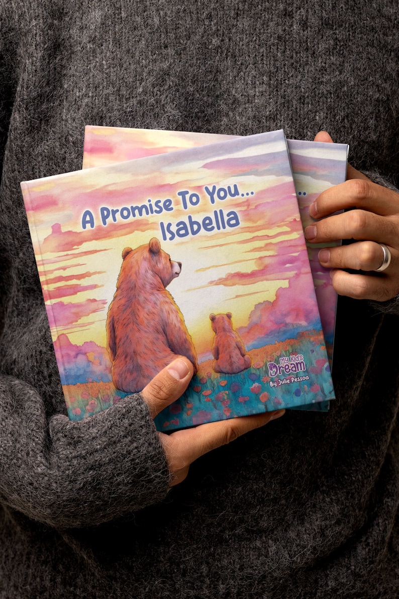 Może przedstawiać: Spersonalizowana książka dla dzieci zatytułowana "A Promise To You... Isabella" z akwarelową ilustracją dw&oacute;ch niedźwiedzi, jednego dużego i jednego małego, siedzących na wzg&oacute;rzu z zachodem słońca w tle. Książka jest częścią serii "My Kid's Dream" autorstwa Julie Pessoa.