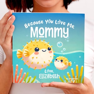 May include: A blue book with the text "Because you love me, Mommy" in white. The book features a cartoon illustration of two yellow pufferfish in the ocean. The text "Love, Elizabeth" is at the bottom of the book.