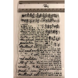 May include: Clear acrylic stamp with musical notes and handwritten script. The stamp includes phrases like "graduation" and "brilliant." A ruler in inches is at the top. Ideal for scrapbooking and card making.