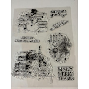 May include: Clear stamp set with Christmas-themed designs. Includes a snowman, Santa Claus, a Christmas tree, and various text elements such as "Christmas Greetings" and "Happiest Christmas Wishes".