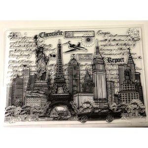 May include: A clear stamp featuring a cityscape with iconic landmarks like the Eiffel Tower and the Statue of Liberty. The design includes text elements such as "Chronicle" and "Report", along with a vintage car and an airplane. The stamp is designed for crafting and scrapbooking.