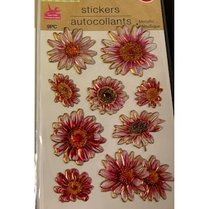 May include: A sheet of nine metallic flower stickers. The stickers feature a pink and red daisy design with gold outlines. The package includes the word "stickers" and "9PC". The stickers are for crafts and scrapbooking.