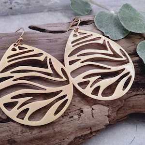 May include: A pair of gold teardrop-shaped earrings with a cut-out design resembling a zebra pattern.