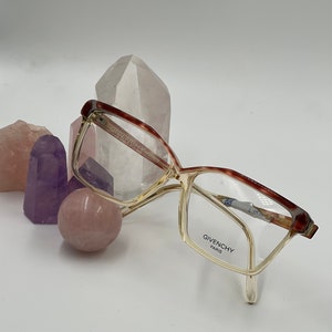 May include: Brown and clear plastic framed eyeglasses with the text "Givenchy Paris" on the right temple.