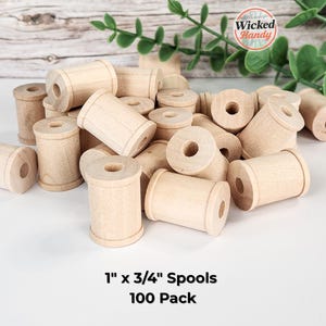 May include: A collection of unfinished wooden spools, each approximately 1 inch by 0.75 inches, scattered on a white surface. The spools are cylindrical with a central hole. The text "1" x 3/4" Spools 100 Pack" is visible.