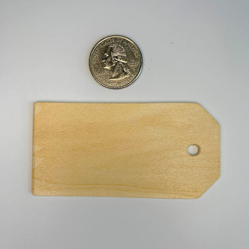 May include: A natural wood tag with a hole in the top. The tag is rectangular with rounded corners and is approximately 2.5 inches wide and 4 inches long.