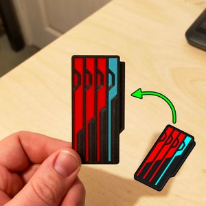 Puede incluir: Un dise&ntilde;o geom&eacute;trico impreso en 3D en negro, rojo y azul. El dise&ntilde;o est&aacute; formado por tres l&iacute;neas verticales con una serie de l&iacute;neas horizontales y curvas.